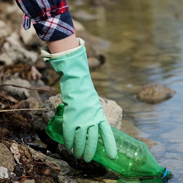 woman wearing heavy gloves participates in shoreline cleanup event