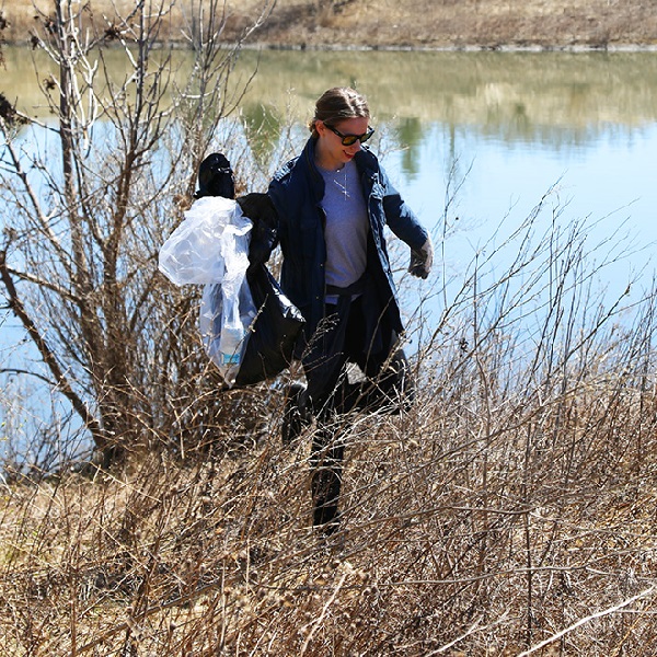 TRCA team member steps carefully over uneven ground while taking part in shoreline cleanup event