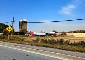 Caledon farm field with trucks and grain silos. 