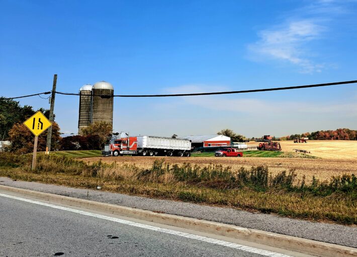 Caledon farm field with trucks and grain silos.