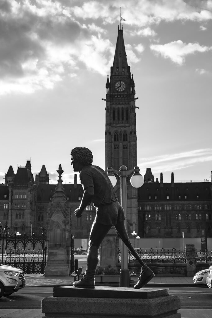 A picture of Terry Fox Memorial Status in front of the Parliament Hill building in Ottawa